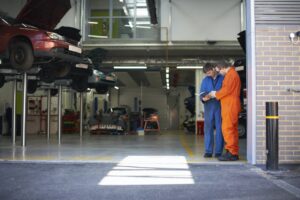 College mechanic students reading manual in repair garage