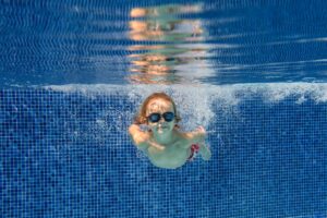 Smiling boy swimming underwater in pool